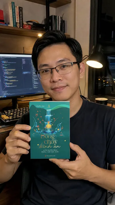 Kỹ sư phần mềm cầm sách ở bàn làm việc buổi tối