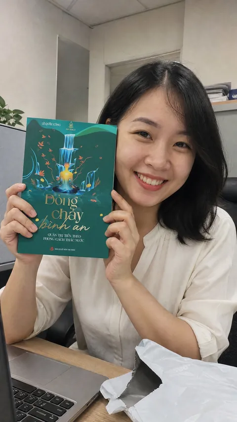 Nhân viên văn phòng cầm sách vừa mở hộp ở bàn làm việc